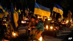 一位乌克兰女士带着女儿在乌克兰西部利沃夫的公墓悼念丈夫。(2023年2月23日)