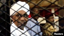 FILE - Sudan's former president Omar Hassan al-Bashir sits inside a cage at the courthouse where he is facing corruption charges, in Khartoum, Sudan August 31, 2019.