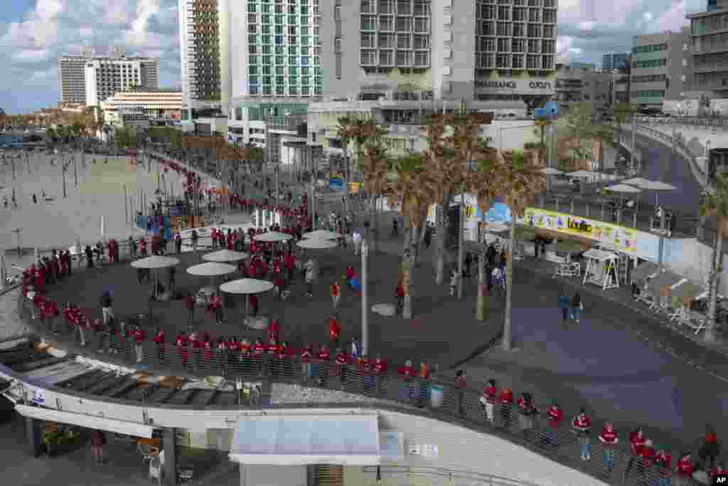 Israeli women&#39;s rights activists form a human chain along the beach to mark International Women&#39;s Day and protest against plans by Prime Minister Benjamin Netanyahu&#39;s new government to change the judicial system, in Tel Aviv.