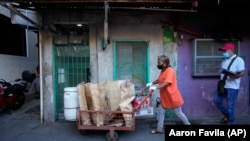 Marilene Capentes pushes her cart of separated garbage along the streets of Malabon, Philippines on Feb. 13, 2023. (AP Photo/Aaron Favila)