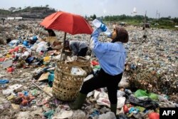 Seorang pemulung meminum air sambil mengumpulkan sampah plastik untuk dijual ke pusat daur ulang di tempat pembuangan sampah di Medan, Sumatra Utara pada 27 Maret 2024. (Foto: AFP)