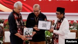 FILE - Ganjar Pranowo, presidential candidate of the ruling Indonesian Democratic Party-Struggle (PDI-P) and his running mate pass their registration documents to the Head of Indonesian Election Commission in Jakarta, Oct. 19, 2023.