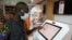 FILE - A man performs a financial transaction at Orange, a French mobile operator based in Abijan, Ivory Coast, September 18, 2020
