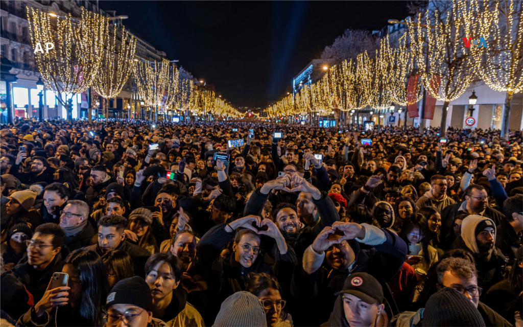 Las personas observan un espectáculo de luces proyectado en el Arco del Triunfo en los Campos Elíseos en París, Francia.