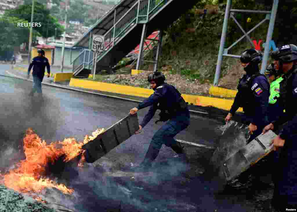 La policía antidisturbios retira una barricada con fuego tras enfrentamientos con manifestantes&nbsp; durante un bloqueo de carreteras contra los resultados electorales en las elecciones presidenciales del domingo en Caracas. 