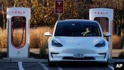 FILE - A Tesla electric vehicle is seen at a Tesla electric vehicle charging station at Willow Festival shopping plaza parking lot in Northbrook, Ill., Dec. 3, 2022.