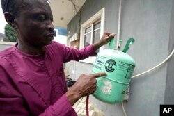 A technician points at an R-22 refrigerant for an air conditioner while working in Lagos, Nigeria, July 18, 2024.