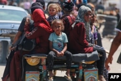 Warga Palestina menaiki gerobak yang ditarik hewan di kawasan perumahan pengungsi di Rafah, di Jalur Gaza selatan, 19 Juni 2024, di tengah konflik antara Israel dan Hamas. (Bashar TALEB / AFP)