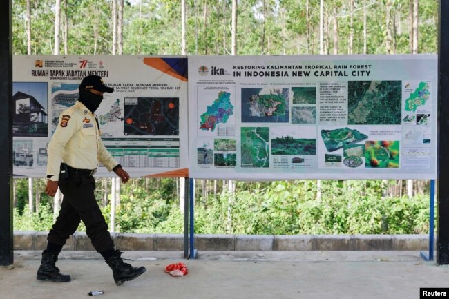 Seorang petugas keamanan berjalan melewati papan informasi di titik nol ibu kota baru, yang dikenal sebagai IKN di Sepaku, Kalimantan Timur, 8 Maret 2023. (Foto: REUTERS/Willy Kurniawan)