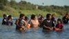 FILE - Migrants navigate around concertina wire along the banks of the Rio Grande after crossing from Mexico into the U.S., Aug. 1, 2023, in Eagle Pass, Texas. 