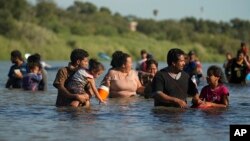 FILE - Migrants navigate around concertina wire along the banks of the Rio Grande after crossing from Mexico into the U.S., Aug. 1, 2023, in Eagle Pass, Texas. 