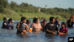 FILE - Migrants navigate around concertina wire along the banks of the Rio Grande after crossing from Mexico into the U.S., Aug. 1, 2023, in Eagle Pass, Texas. 