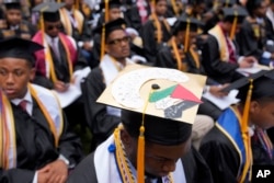 Valedictorian DeAngelo Jeremiah Fletcher shows his mortarboard with a protest image representing a Palestinian flag as President Joe Biden speaks to graduating students at the Morehouse College commencement, May 19, 2024, in Atlanta, Georgia.