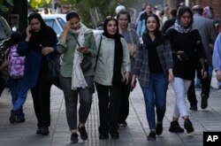 Iranian women, some without wearing their mandatory Islamic headscarves, walk in downtown Tehran, Sept. 9, 2023.