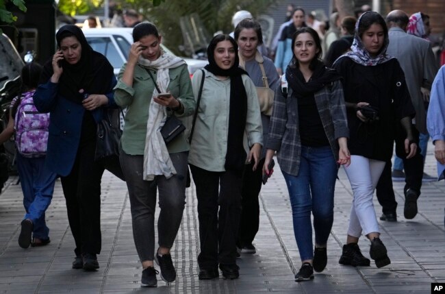 Iranian women, some without wearing their mandatory Islamic headscarves, walk in downtown Tehran, Sept. 9, 2023.