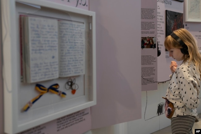 A child listens to audio with a video at the War Diaries exhibition, showcasing the personal diaries of Ukrainian children who have witnessed the war, hosted by the Amsterdam city hall , Netherlands, Thursday, Aug. 17, 2023. (AP Photo/Peter Dejong)