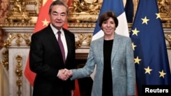2023年2月15日中共中央外事委員會主任王毅在法國巴黎出席會議時與法國外交和歐洲事務部長卡特琳·科隆納握手。