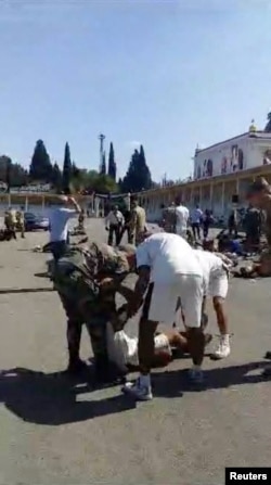 People help a wounded person after a drone attack on a military academy in Homs, Syria, Oct. 5, 2023, in this screen grab from a video obtained by Reuters.
