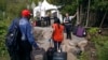 FILE - A Royal Canadian Mounted Police officer informs a migrant couple of the location of a legal border station, shortly before they illegally crossed from Champlain, New York, to Saint-Bernard-de-Lacolle, Quebec, using Roxham Road, Aug. 7, 2017.