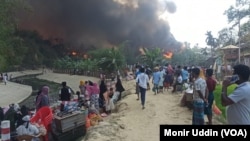 Rohingya refugees bring out their belongings and watch as fire guts through shanties in Balukhali refugee camp in Bangladesh, March 5, 2023.