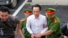 FILE - Trinh Van Quyet, a prominent Vietnamese business tycoon, is escorted to a court for his trial of defrauding stockholders, in Hanoi, July 22, 2024. 