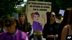 Women walk close to a banner reading "Domestic workers we do not agree with the Government," during a May Day rally in Pamplona, northern Spain, May 1, 2023.