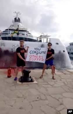 In this frame from video provided by Karen Killeen, protesters demonstrate in front of a super yacht belonging to Walmart heir Nancy Walton Laurie after spray painting it in Ibiza, Spain on July 16, 2023.