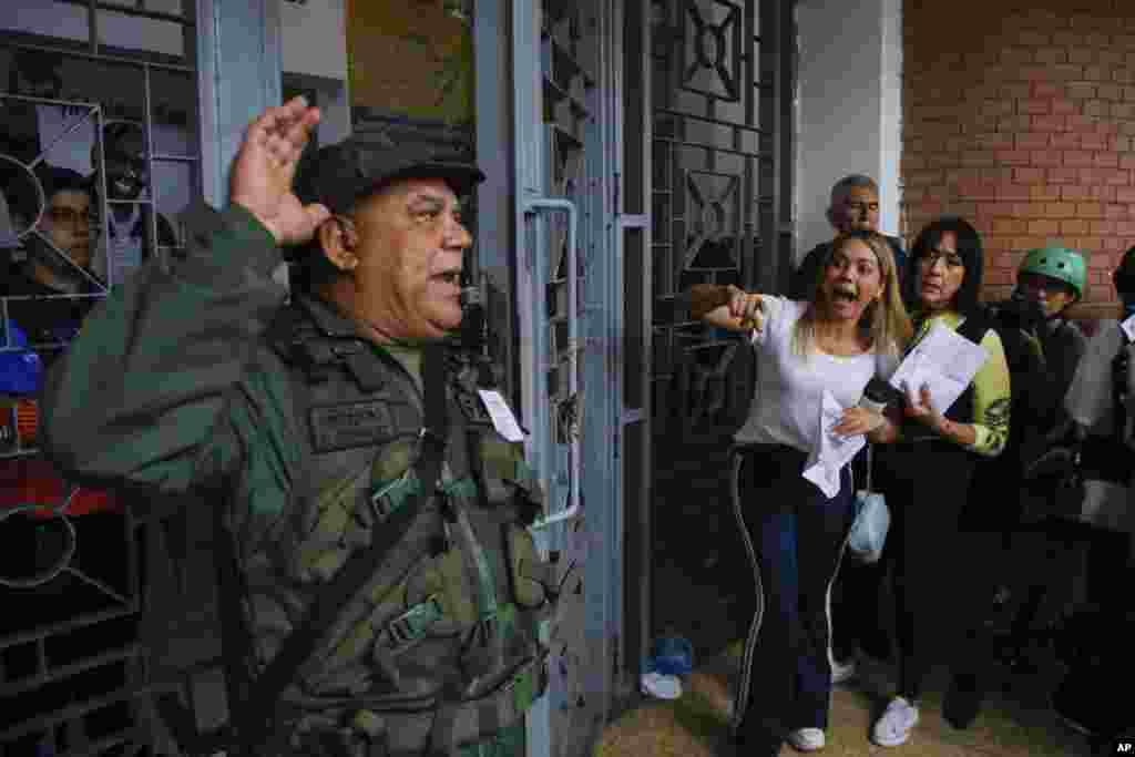 A National Guard officer addresses voters lining up at the Andres Bello School as opposition poll watchers argue they are not being allowed to enter the voting center during the presidential elections in Caracas, Venezuela.