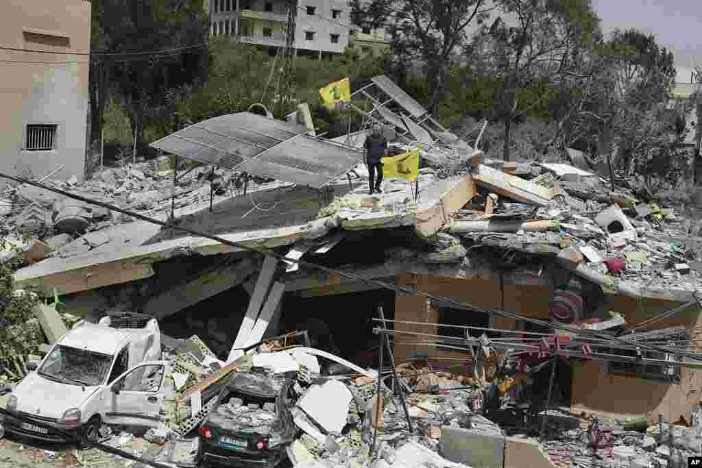 A man stands on a house that was destroyed by an Israeli airstrike, in Hanine village, south Lebanon. Hezbollah militants and Israeli forces have been exchanging fire since a day after the Israel-Hamas war began on October 7.