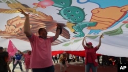 Mexican opposition supporters hold up a flag during a rally, protesting what they claim are attempts by President Andres Manuel Lopez Obrador to divide the country, in the Zocalo, Mexico City, May 19, 2024. 