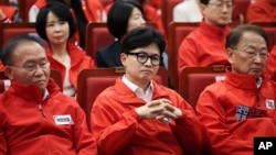 The ruling People Power Party's leader Han Dong-hoon, center, and party members watch TV broadcasting results of exit polls for the parliamentary election at the National Assembly, April 10, 2024 in Seoul, South Korea.