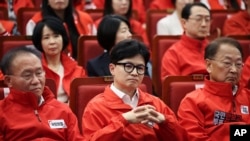 Ông Han Dong-hoon, giữa, lãnh đạo Đảng Quyền lực Nhân dân Hàn Quốc đang theo đội kết quả thăm dò ngoài phòng phiếu trong cuộc bầu cử Quốc hội hôm 10/4 năm 2024 