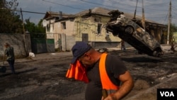 在库皮扬斯克市中心，市政工人正在清理被俄罗斯火箭弹袭击摧毁的汽车残骸。(2023年8月21日，美国之音博夏特拍摄)
