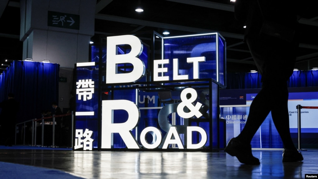 FILE - A woman walks in front of a sign at the 'Belt and Road' summit in Hong Kong, Sept. 14, 2023. What started as an effort to rebuild old Silk Road trade routes through Central Asia is now reaching every continent and the North and South Pole regions.