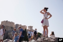 Tourists stand at the Aeropagous hill in front of the ancient Acropolis, in central Athens on Wednesday, June 12, 2024. The ancient site of Acropolis is closed to the public on Wednesday. (AP Photo/Petros Giannakouris)