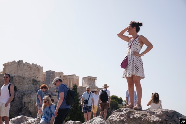 Tourists stand at the Aeropagous hill in front of the ancient Acropolis, in central Athens on Wednesday, June 12, 2024. The ancient site of Acropolis is closed to the public on Wednesday. (AP Photo/Petros Giannakouris)