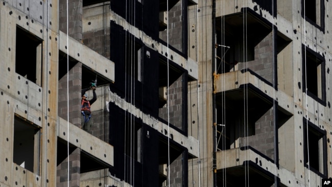 FILE - A worker uses a drill during construction of new apartment buildings in Beijing, China, Oct. 26, 2021.