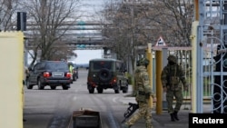 FILE - Russian service members guard the entrance to the Zaporizhzhia nuclear power plant in the Zaporizhzhia region, Russian-controlled Ukraine, March 29, 2023. The plant faces "a relatively dangerous situation" after a dam burst in Ukraine, a U.N. official said on Tuesday.