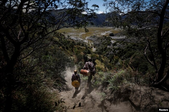 Pria Hindu Tengger membawa alat musik tradisional saat berjalan menuruni gunung usai melakukan "Mendhak Tirta", menjelang festival Yadnya Kasada di Taman Nasional Bromo Tengger Semeru, Pasuruan, Jawa Timur, 19 Juni 2024. (REUTERS/Willy Kurniawan)