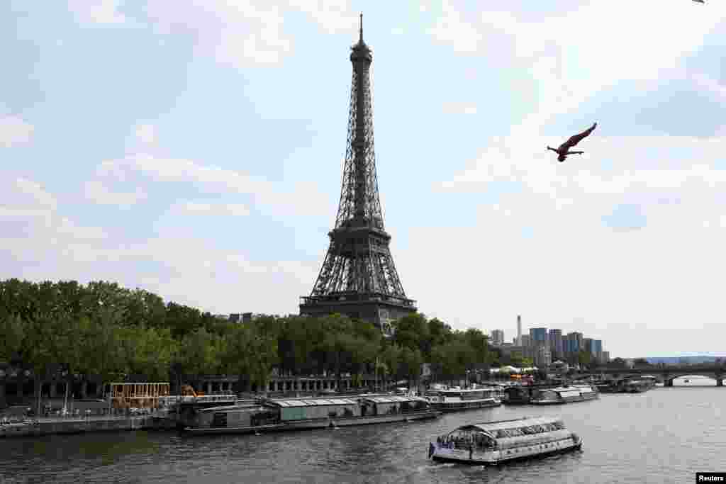 An athlete dives off the Port Debilly on the banks of the Seine River in front of the Eiffel tower during a training ahead of the competition Red Bull Cliff Diving World in Paris, France.