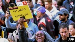 FILE: Protesters lift placards during a demonstration in Tunis on February 25, 2023, against controversial remarks by the Tunisian President regarding illegal migrants that critics said were openly racist.