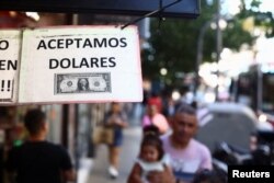 Sebuah tanda di luar toko bertuliskan dalam bahasa Spanyol "Kami menerima Dolar" di Buenos Aires, Argentina, 12 Desember 2023. (REUTERS/Tomas Cuesta)