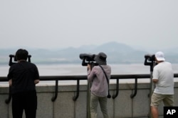 Pengunjung menggunakan teropong untuk melihat sisi Korea Utara dari observatorium unifikasi di Paju, Korea Selatan, Jumat, 21 Juni 2024. (AP/Lee Jin-man)