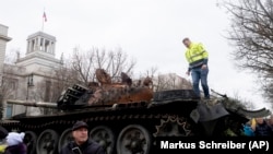 Rongsokan tank T-72 milik Rusia yang hancur dalam perang di Ukraina ditempatkan di depan Kedutaan Rusia di Berlin, Jerman, dalam aksi protes memperingati invasi Rusia ke Ukraina, pada 24 Februari 2023. (Foto: AP/Markus Schreiber)