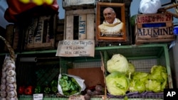 A picture of Pope Francis hangs beside a sign that reads in Spanish "With debit card 7%, with credit 12% increase," at a vegetable and fruit market in Buenos Aires, Argentina, May 11, 2023.