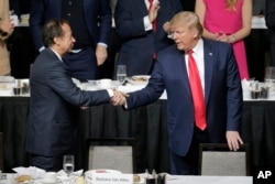 FILE - Then-President Donald Trump, right, shakes hands with billionaire investor John Paulson in New York on Nov. 12, 2019. Trump's campaign said it raised $50.5 million at an event with major donors at Paulson's Florida home on Saturday.