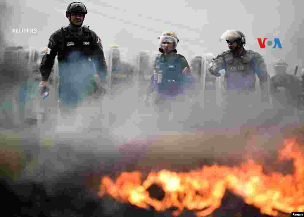 La policía antidisturbios en Caracas hace guardia junto a una barricada tras los enfrentamientos con los manifestantes durante un bloqueo de carreteras contra los resultados electorales en Venezuela.