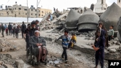 People walk past the rubble of Al-Faruq Mosque, that was destroyed during Israeli bombardment, in Rafah on the southern Gaza Strip on March 17, 2024.