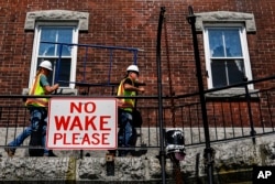 Larry Gaylord and DJ Dorbert carry a piece of scaffolding at the Hudson-Athens Lighthouse, June 12, 2024, in Hudson, New York.