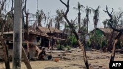 (FILE) A woman cooking next to destroyed houses and burned trees following fighting between Myanmar's military and the Arakan Army (AA) ethnic minority armed group in Rakhine State, May 21, 2024 